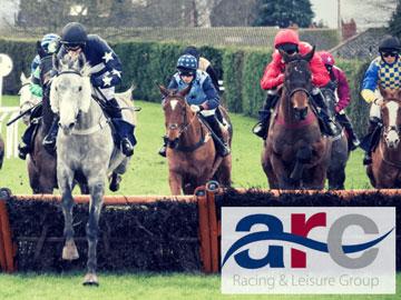Jockeys jumping over a hurdle during a race at Hereford Racecourse.