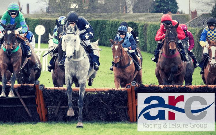 Jockeys jumping over a hurdle during a race at Hereford Racecourse.