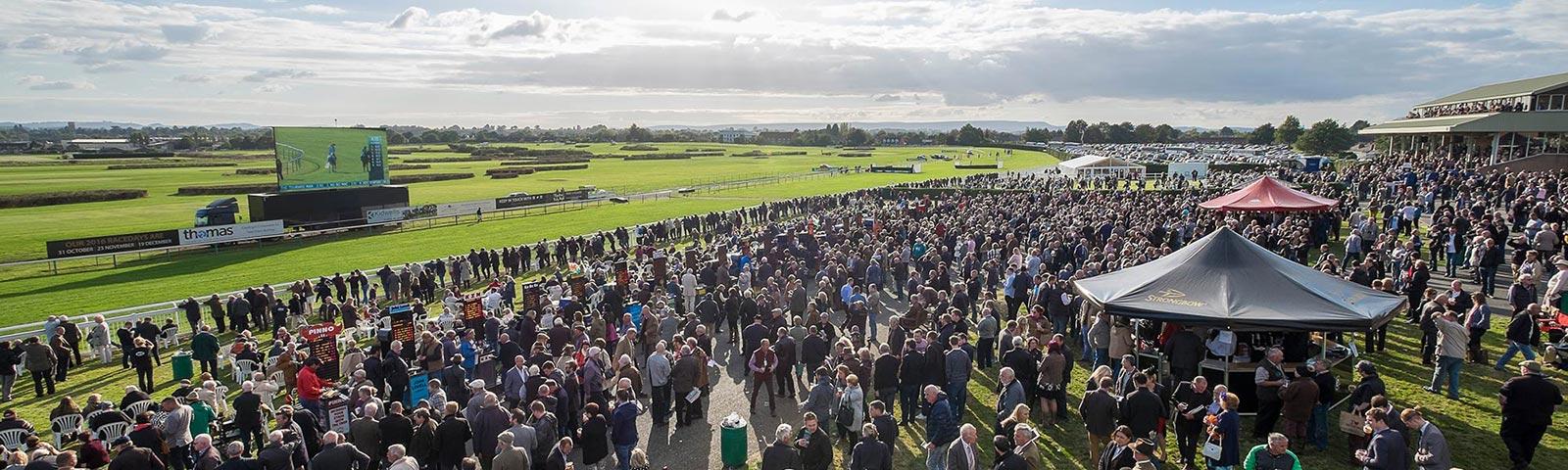 Crowds watching racing at Hereford Racecourse.