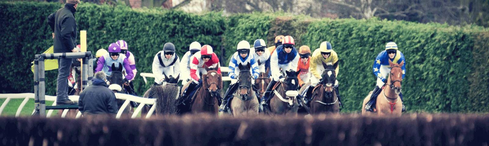 A group of jockeys racing at Hereford Racecourse.